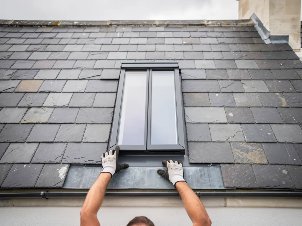 A roofer dressing slates round a new conservation rooflight