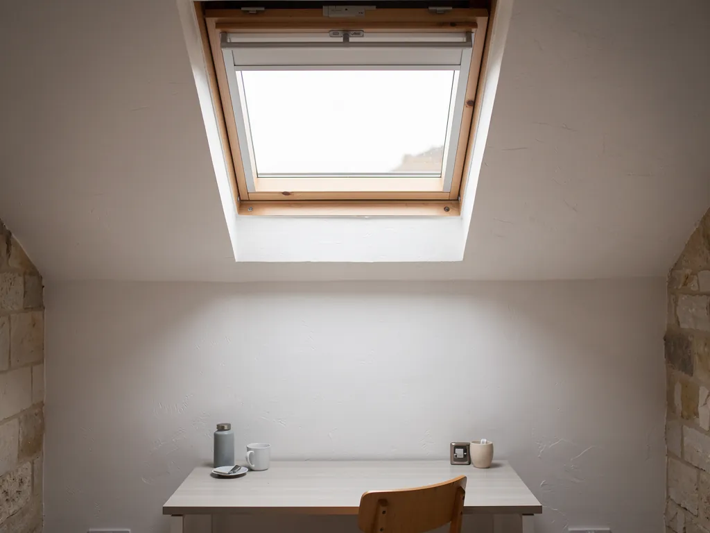 A manual roof window with its handle bar in a loft room, before conversion to electric