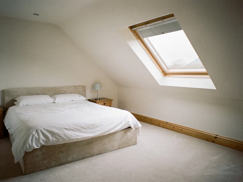 A large roof window, big enough for escape, above a low loft room