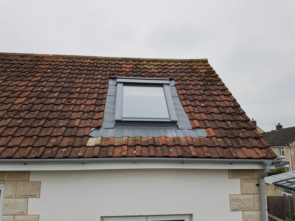 The flashing dressed round a new roof window in a clay tiled roof