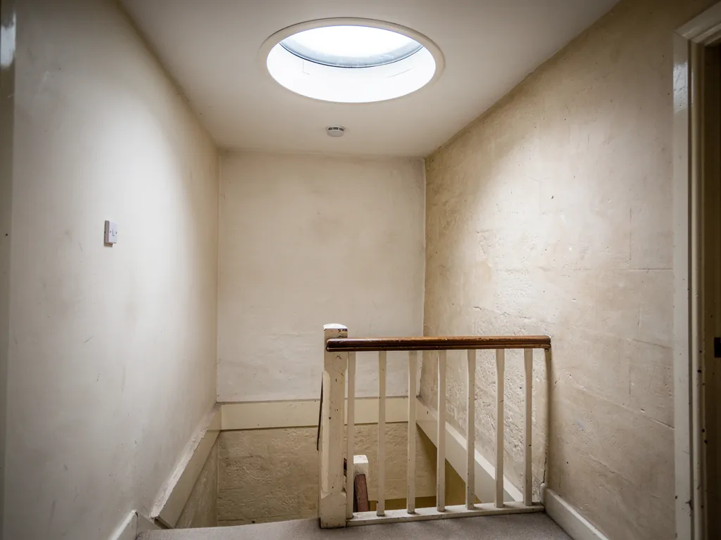 A round sun tunnel diffuser glowing in a landing ceiling