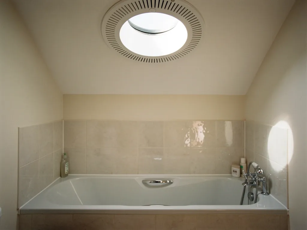 A sun tunnel diffuser with a ventilation ring in a bathroom ceiling