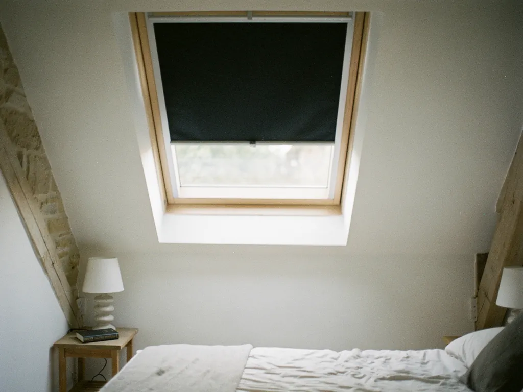 A blackout blind half drawn on a roof window
