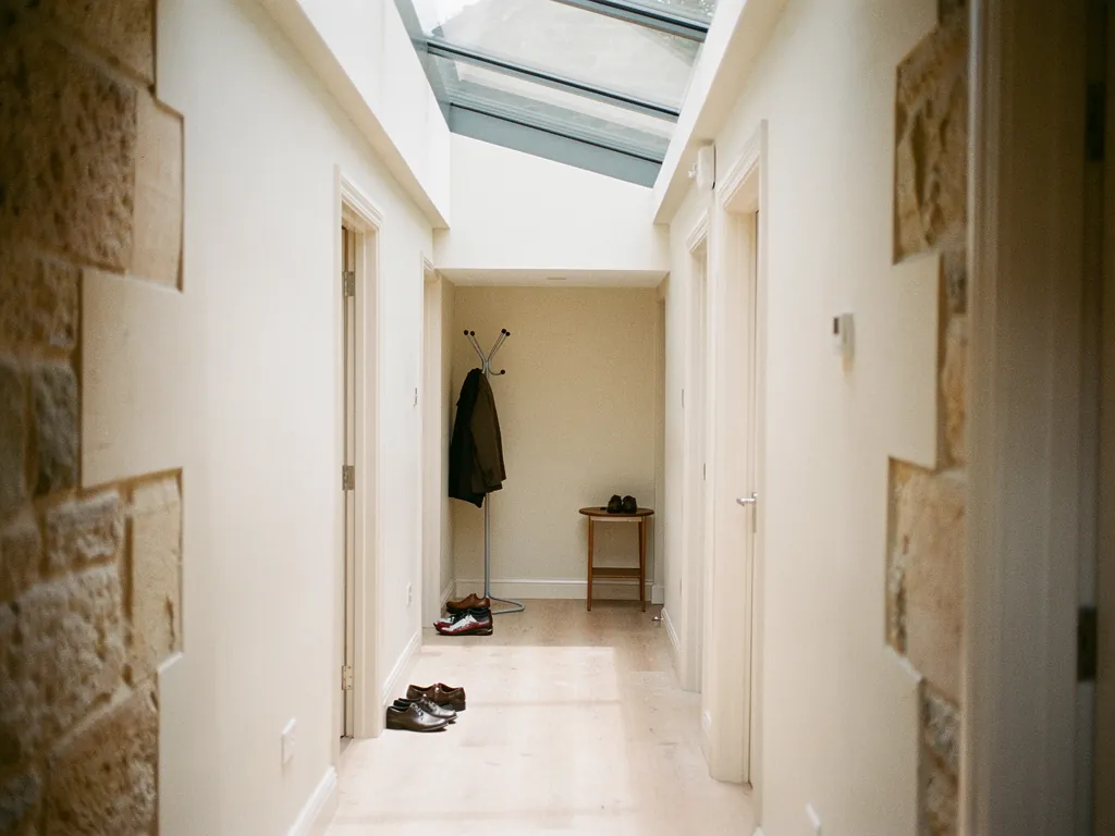 A narrow hallway lit by a walk-on glass rooflight above